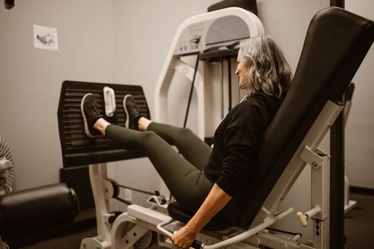Woman over 50 using a leg press machine in a gym, focused and determined