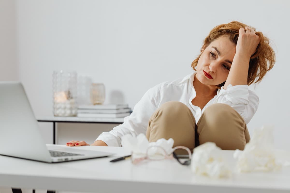 Woman sitting at a desk looking overwhelmed and exhausted