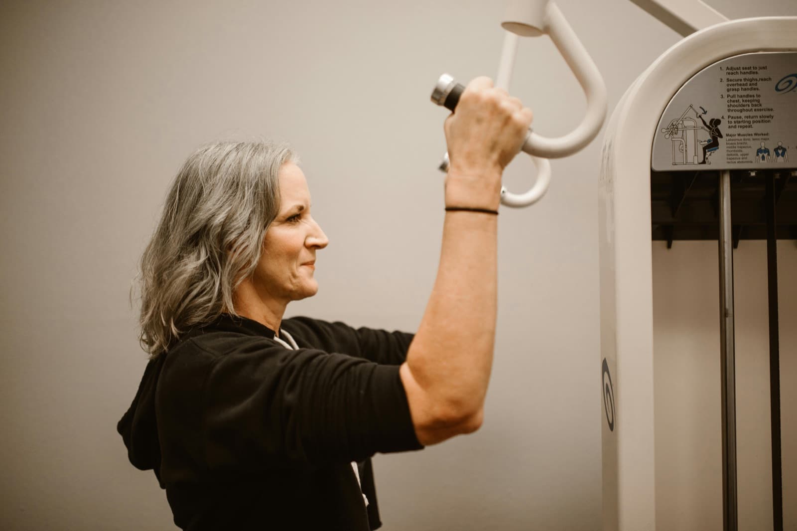 Woman over 50 working out with weights in a gym