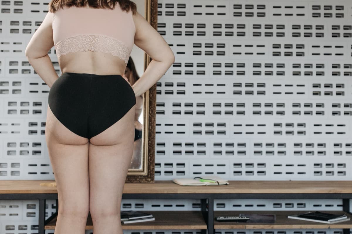 Woman standing in front of a mirror, looking at changes in her body