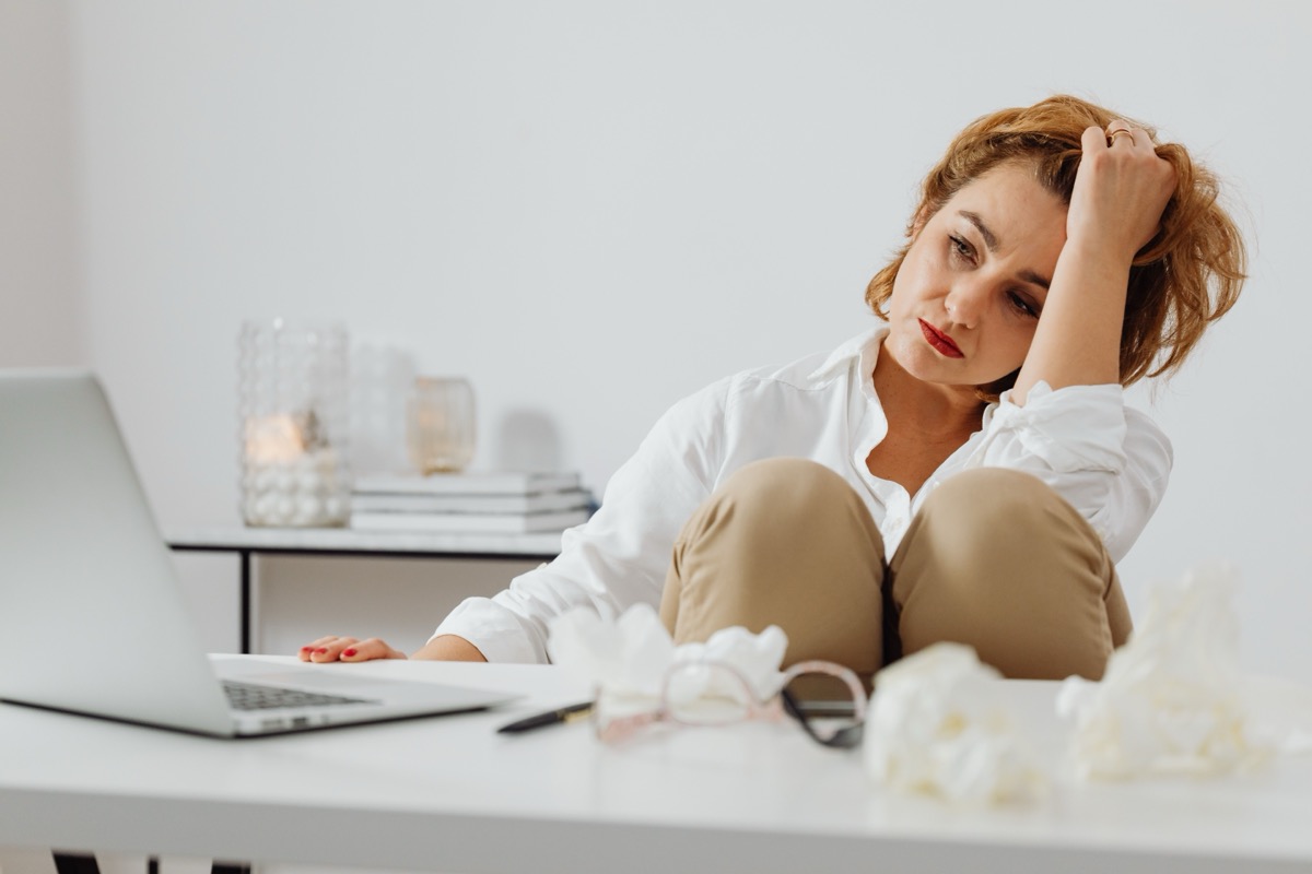Woman sitting at a desk looking overwhelmed and exhausted